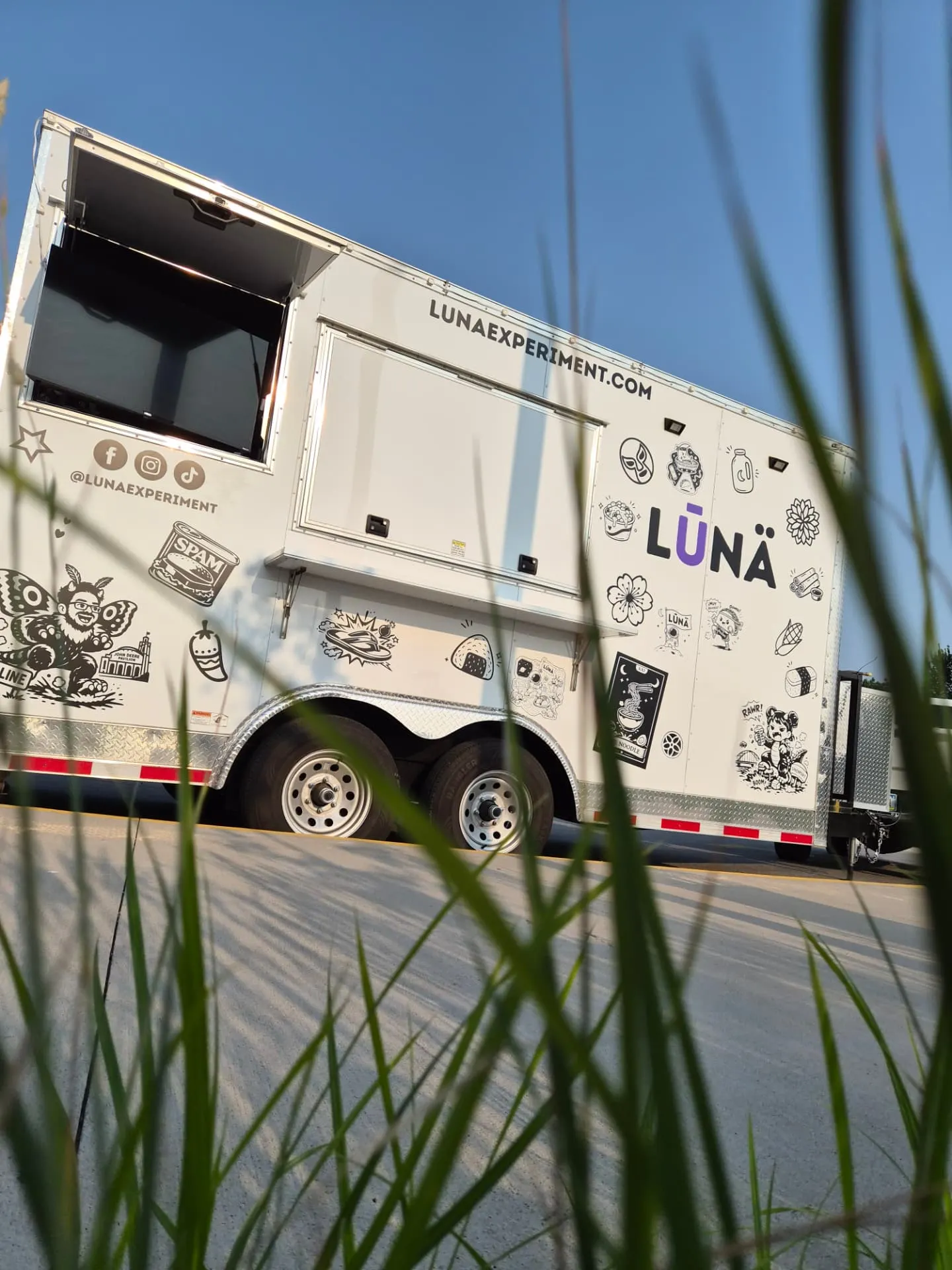 The LŪNÄ trailer parked outdoors, its side covered in black-and-white sticker illustrations